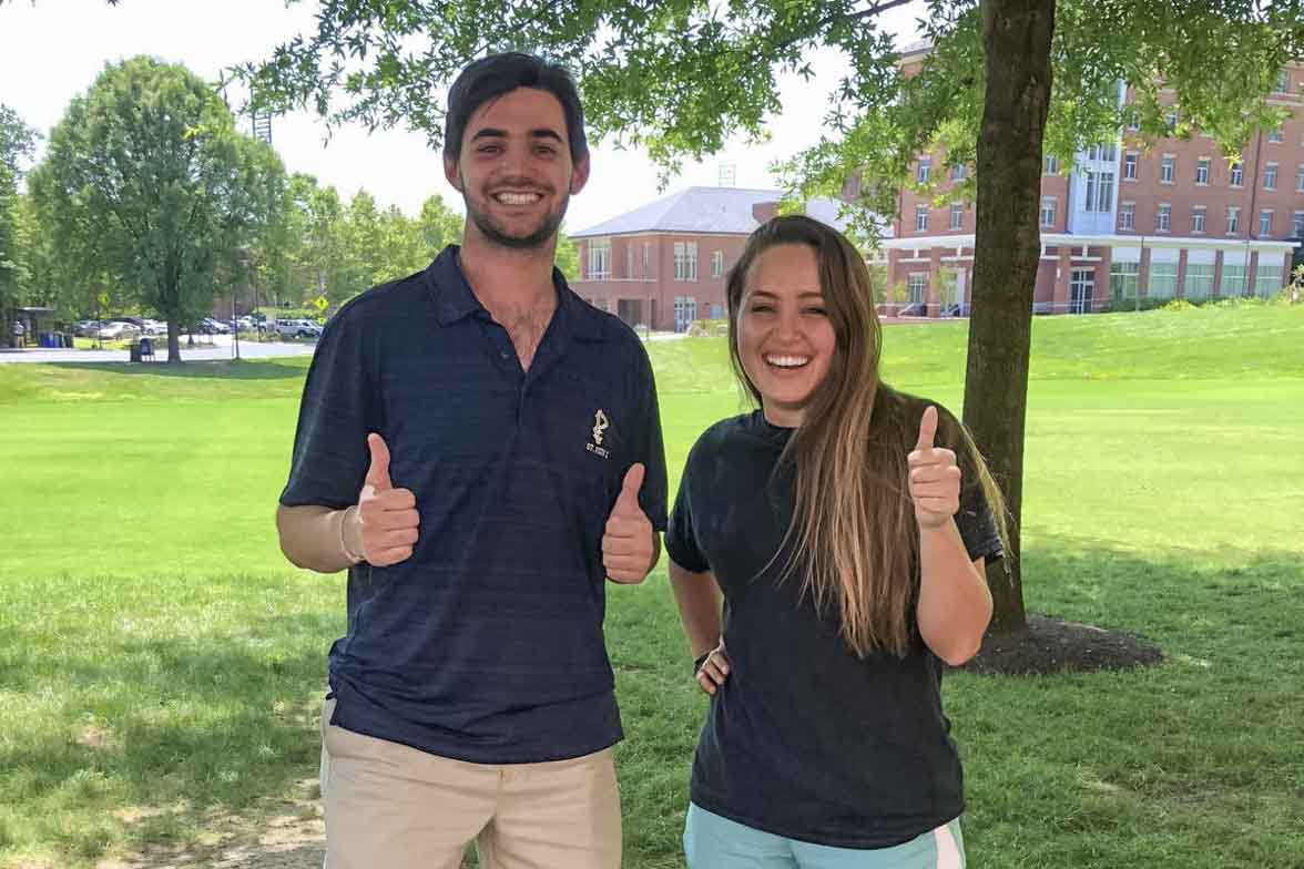 Joe Reigner, left, and Rachel Clark, right stand together giving the camera a thumbs up