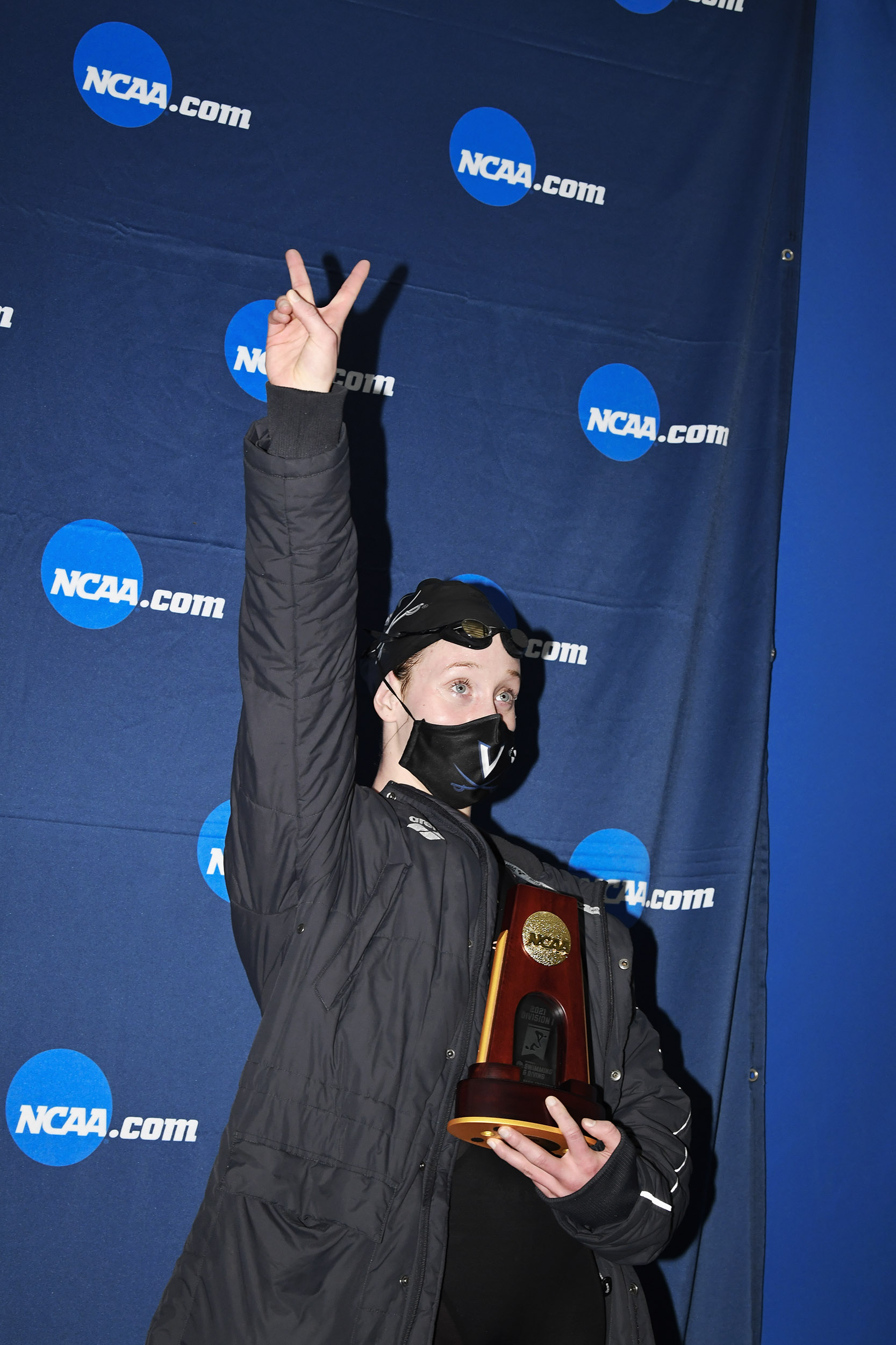 Paige Madden raising her arm while holding the NCAA trophy