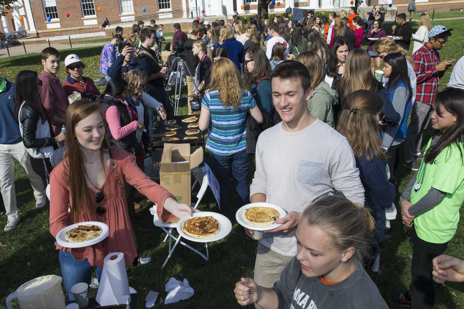 Students handing out pancakes to other students