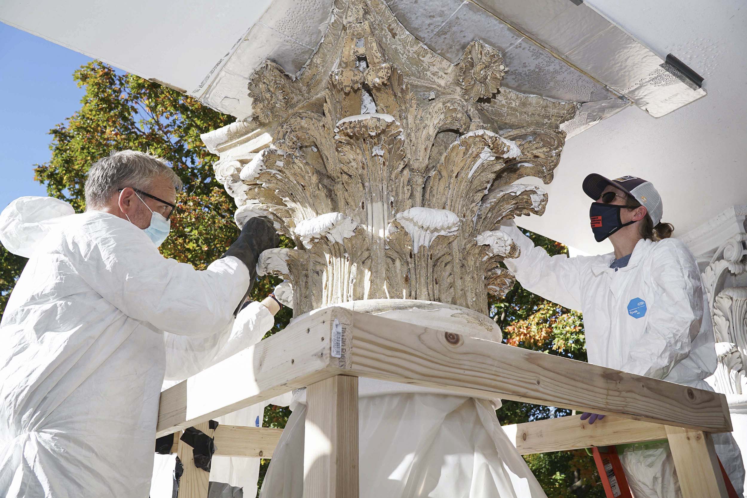 Dunsmore, left, and Leigh Hassler, right, working on removing pain from a marble column