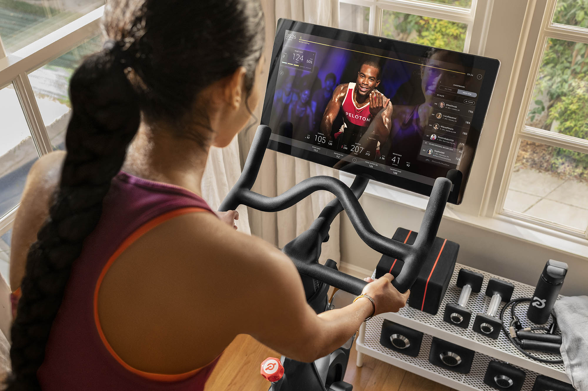 Woman riding a peleton bike during a class led by an instructor