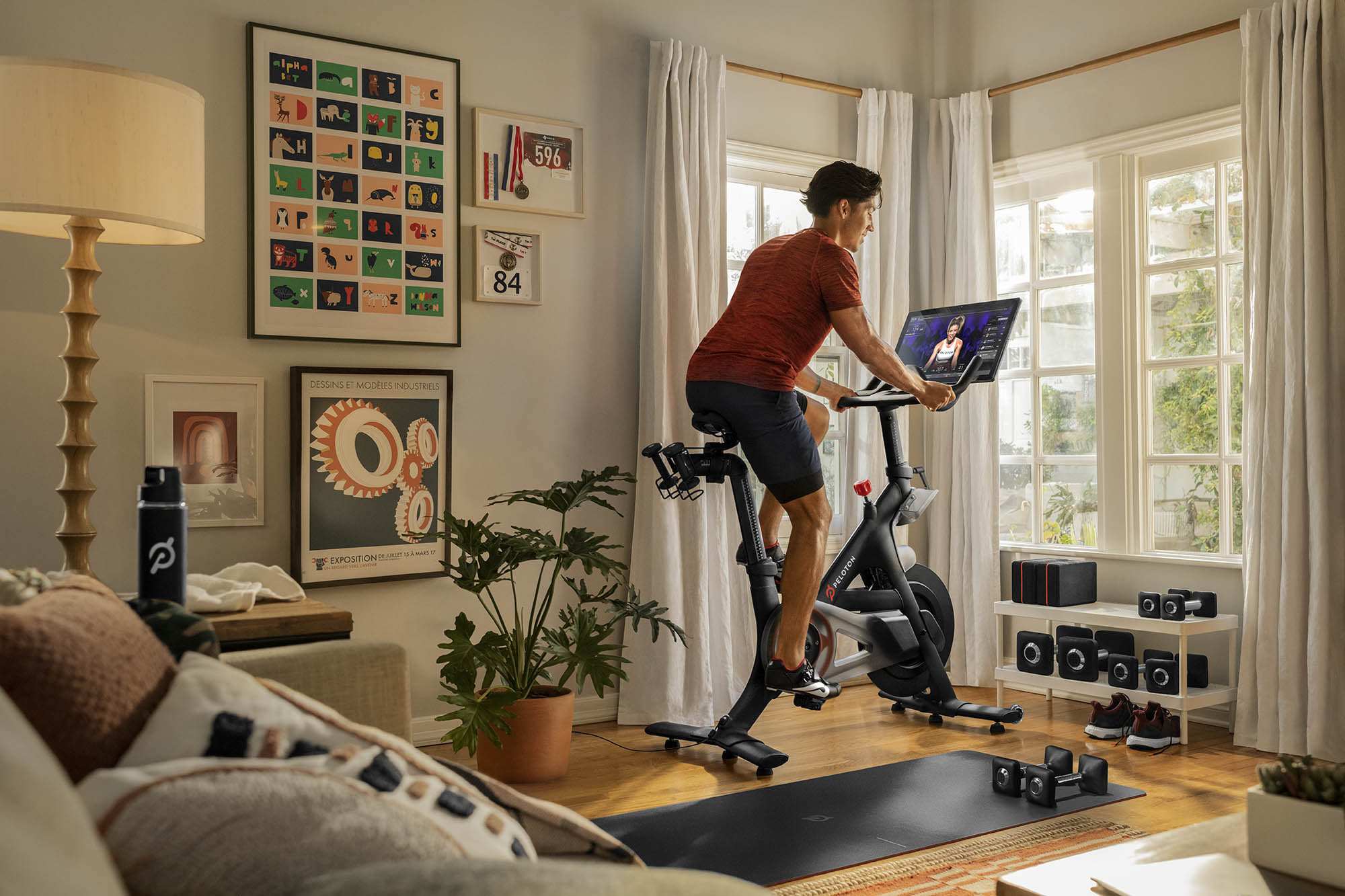 Man riding a peloton bike in his living room near windows