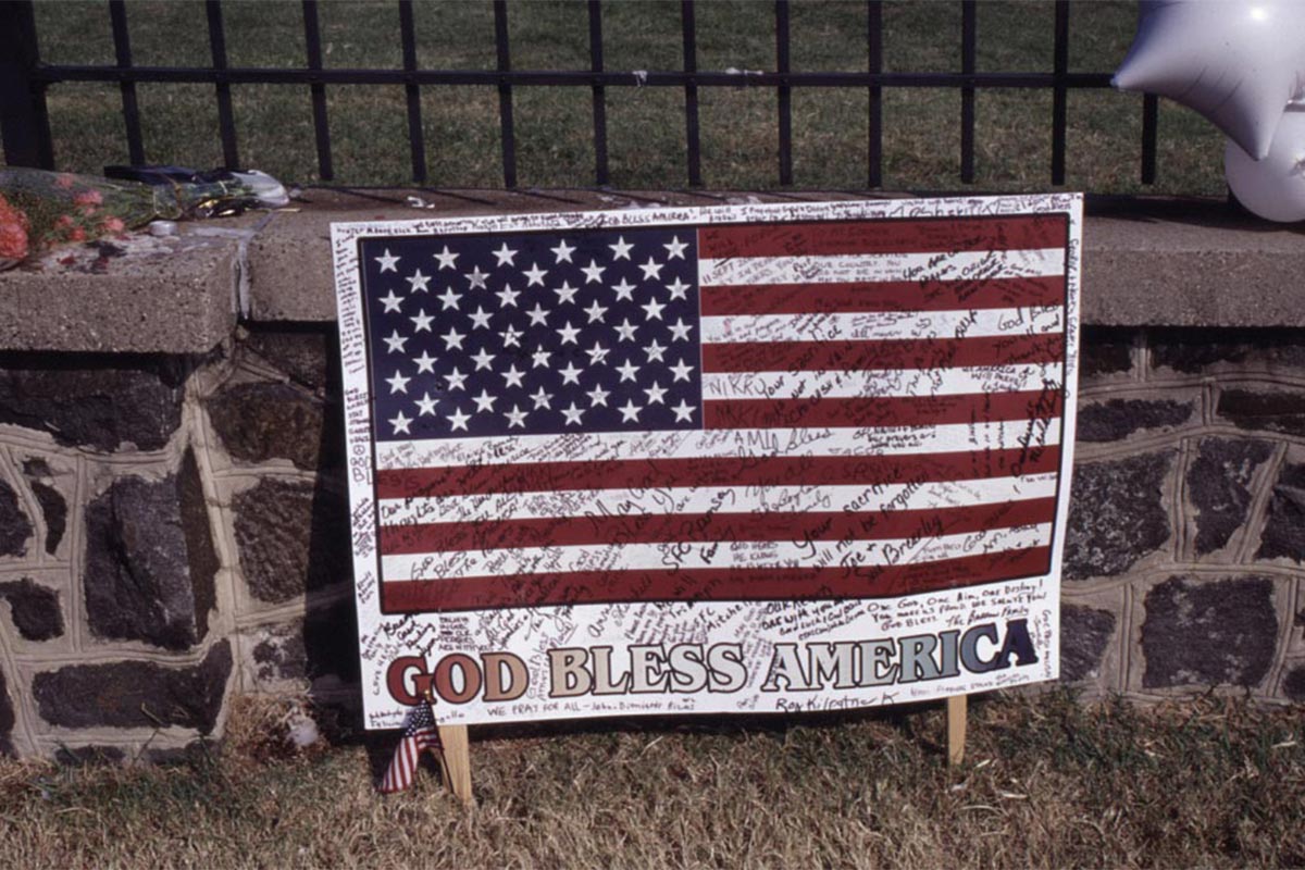 American Glad poster with the text God Bless America with hundreds of signatures sitting outside of the Pentagons brick wall