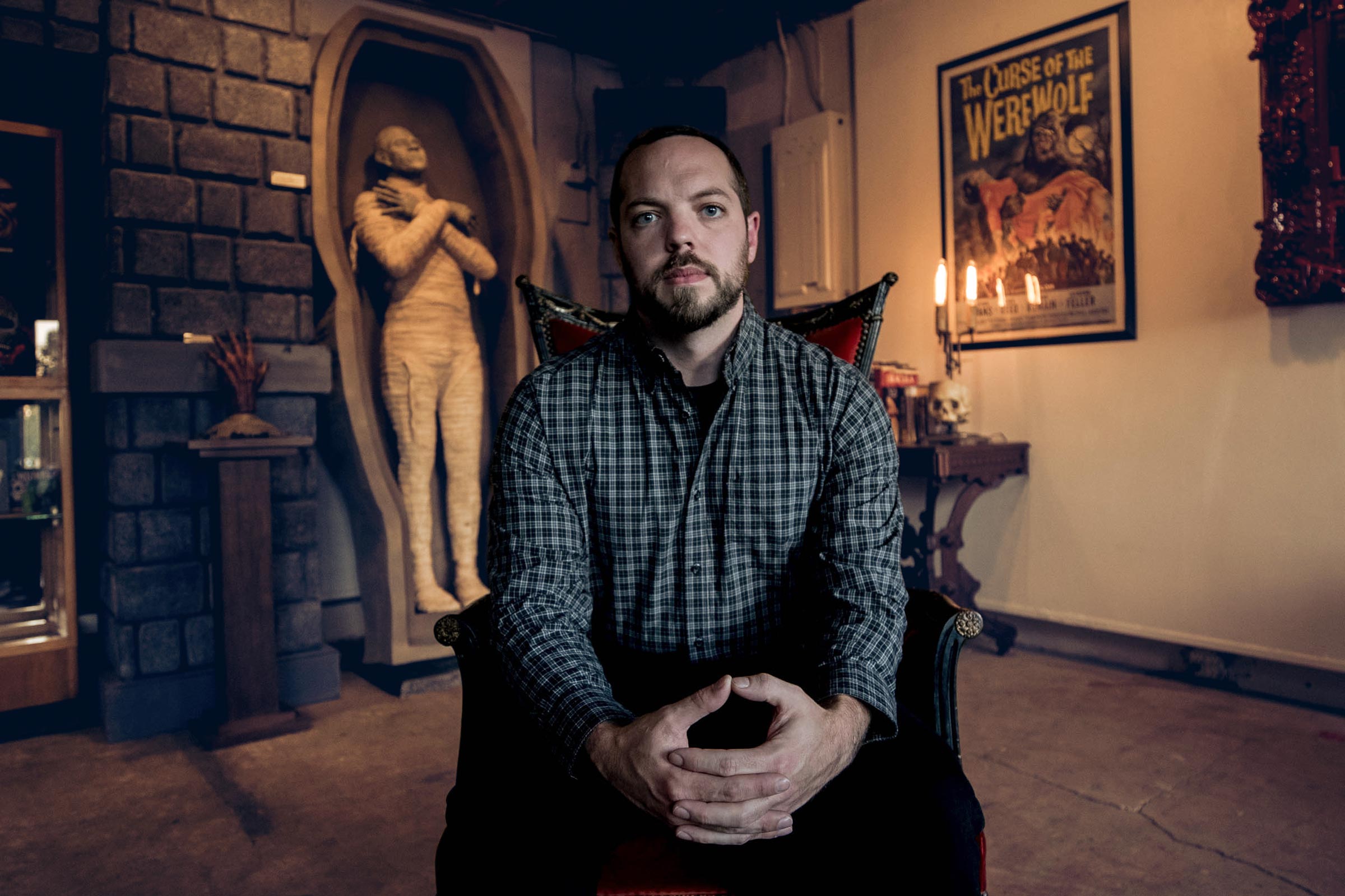 Portrait of a man in a chair in a horror-themed gallery