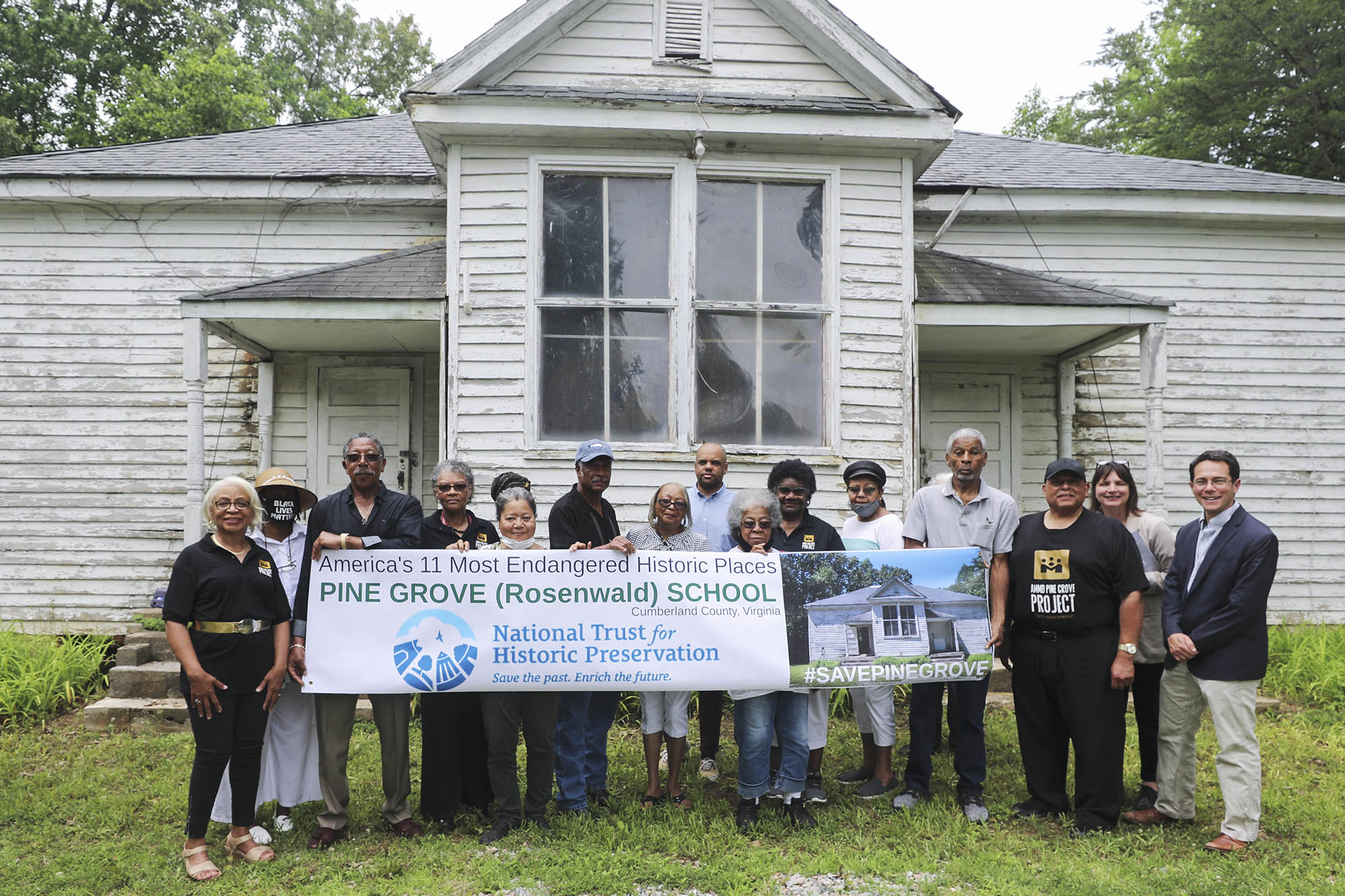Group of community members outside of the Pine Grove school holding a banner that reads: America's 11 most endangered historic places Pine Grove (Rosenwald) School