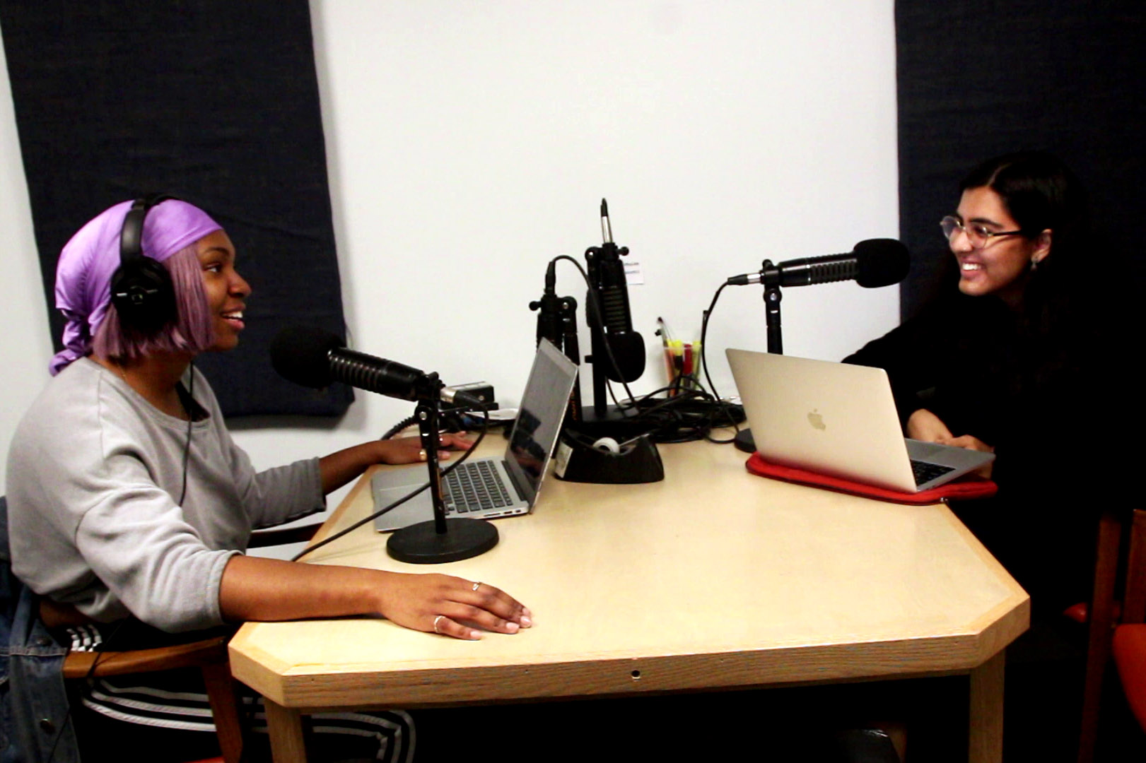 Elizabeth Bangura, left, and Marwah Shauib, right sitting at a table with headphones and microphones