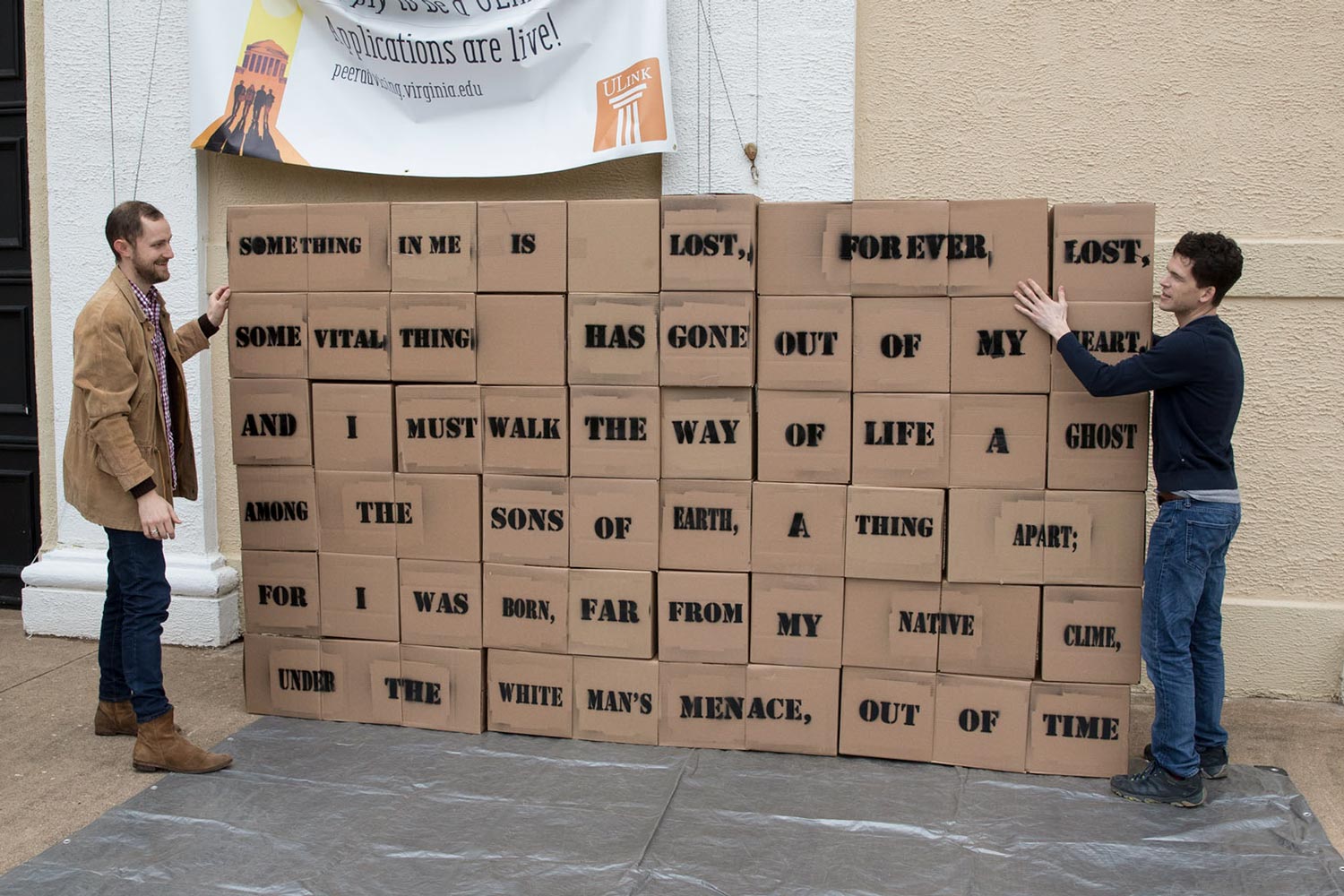 Neal Curtis, right and Jordan Burke, left, stack boxes that has words written on them in a poem.  Some of the words are hard to read