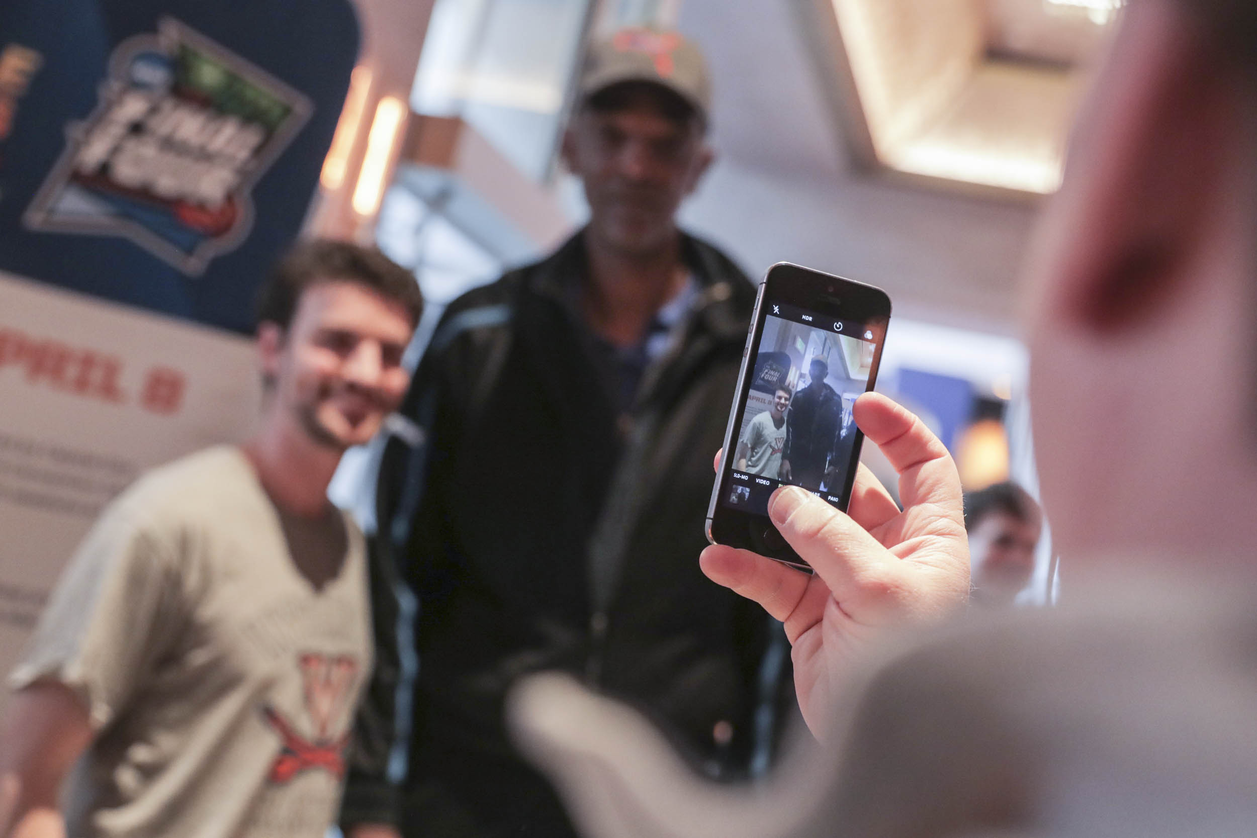 Person taking a picture of Ralph Sampson and a fan with their phone