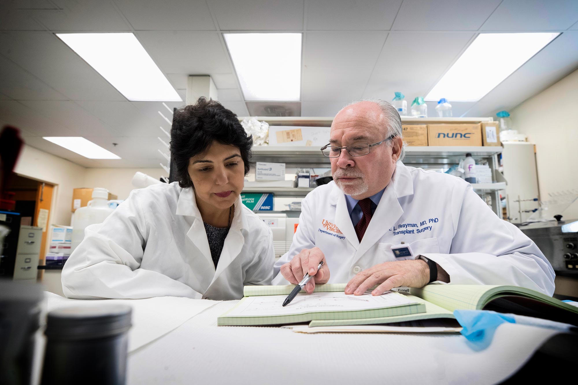Preeti Chhabra, left, and  Dr. Kenneth Brayman, right look in a book together