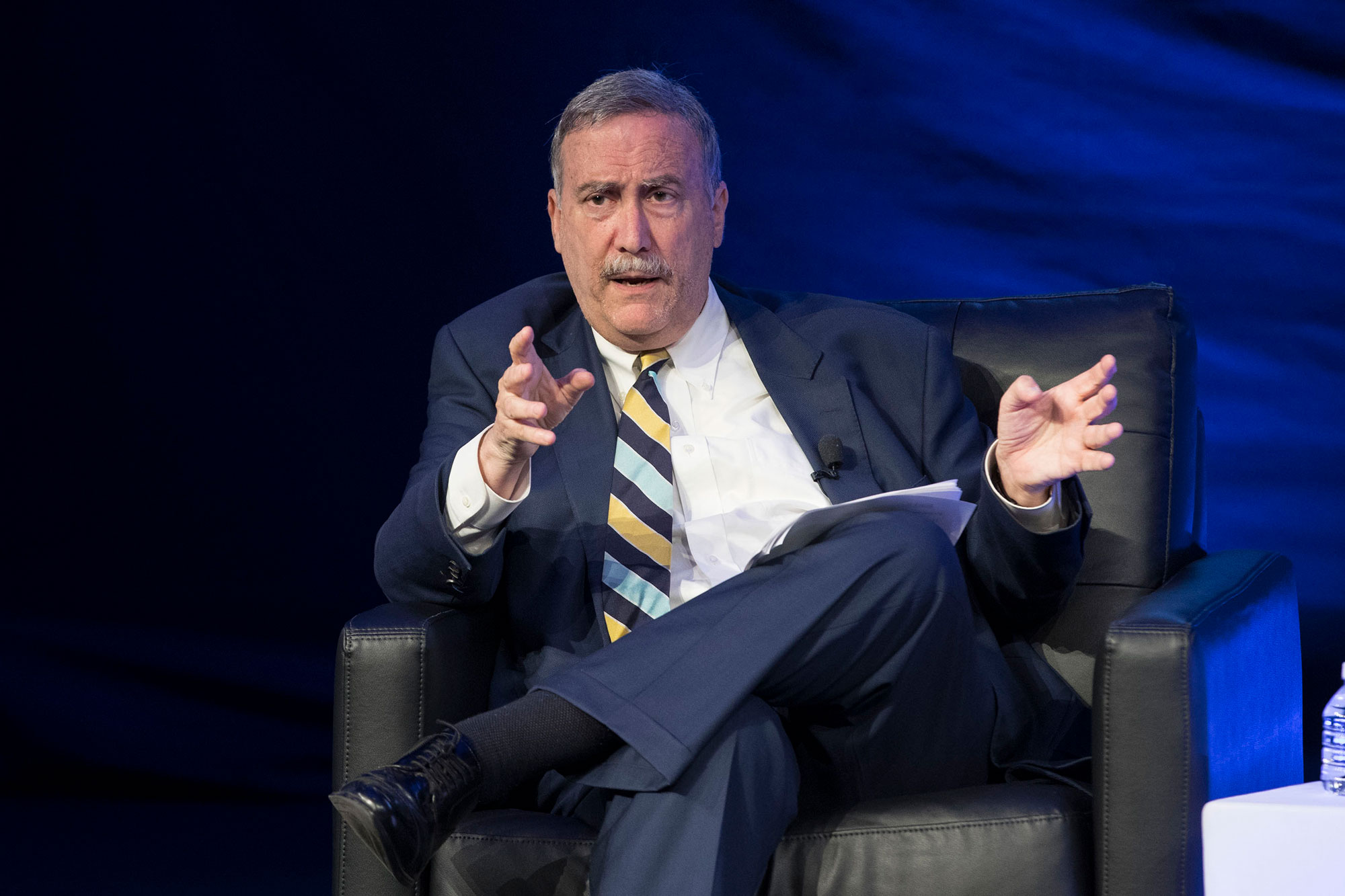 Larry Sabato sits in a chair on stage during a panelist discussion