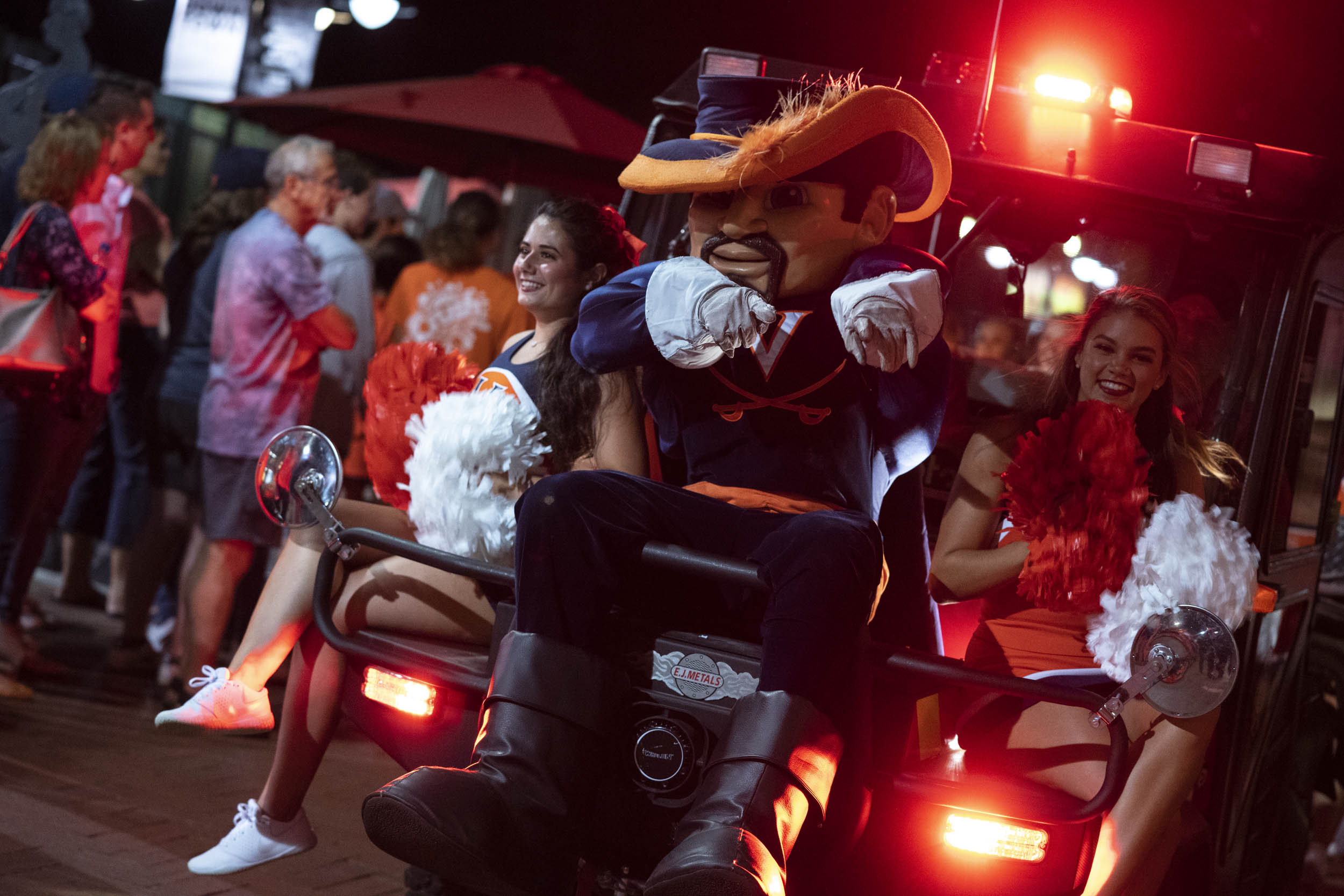 Cav Man sits on a golf cart with cheerleaders