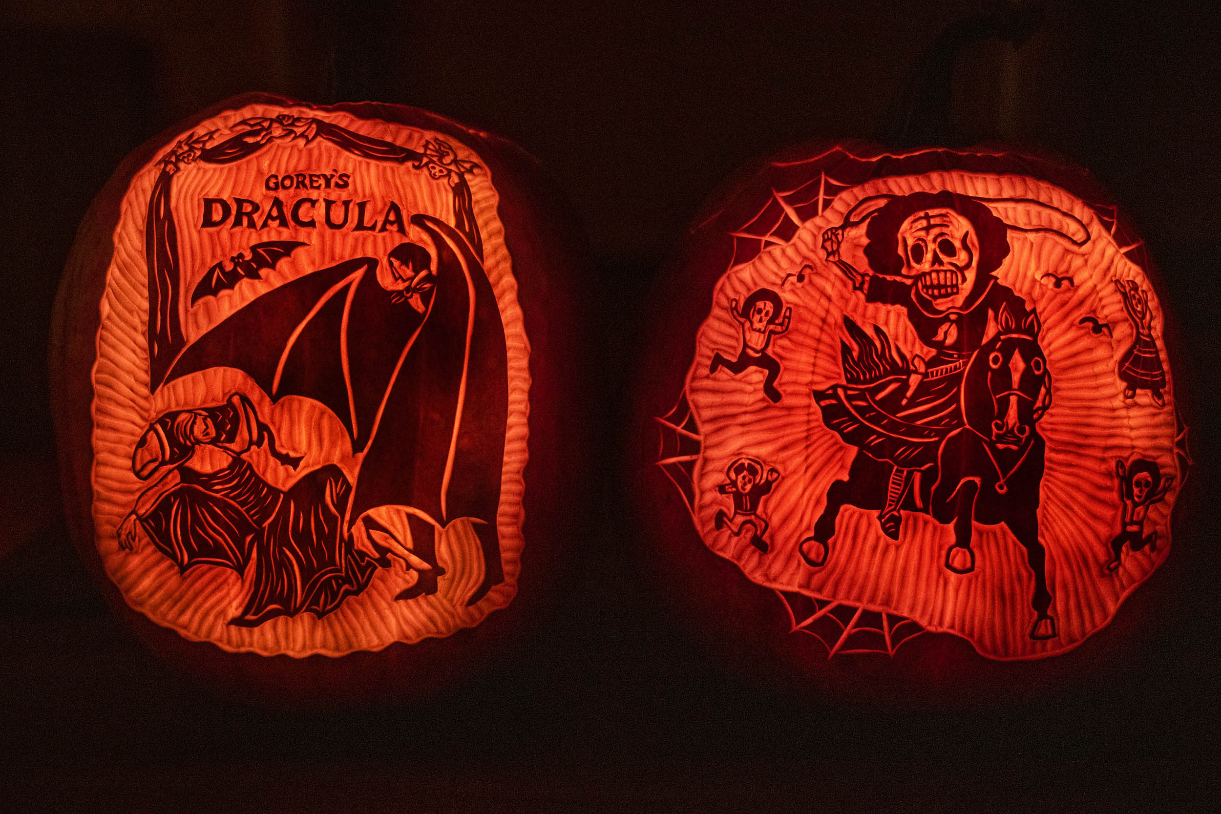 Left pumpkin: Dracula getting ready to bite a woman Right pumpkin: headless horseman riding a horse