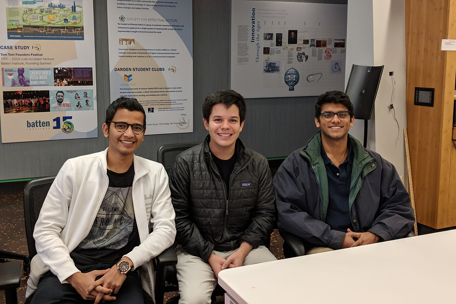 Raahish Kalaria, Victor Layne and Aneesh Dhawan sit in chairs smiling at the camera