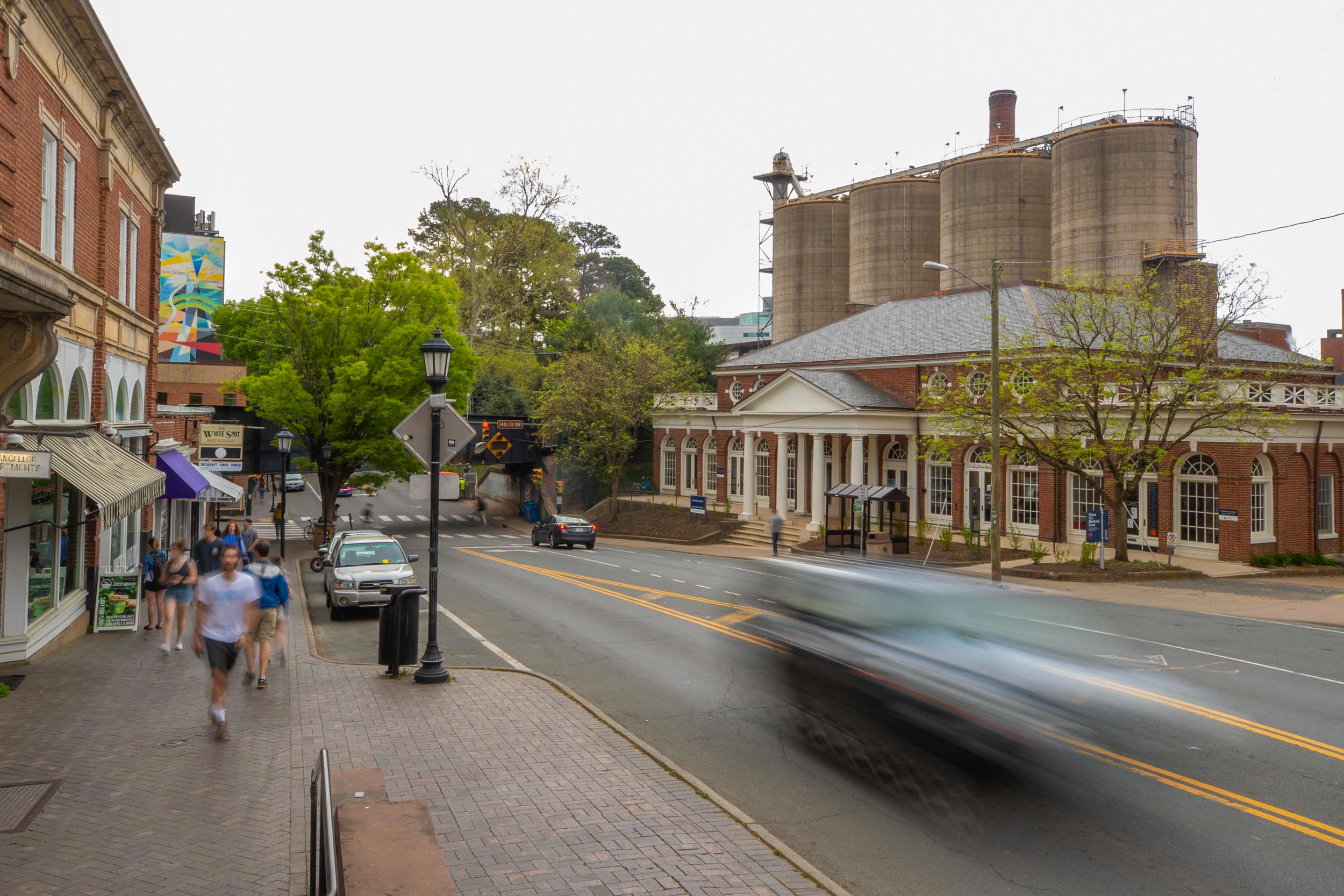 Street view of people walking down a rainy sidewalk in Charlottesville near the Corner