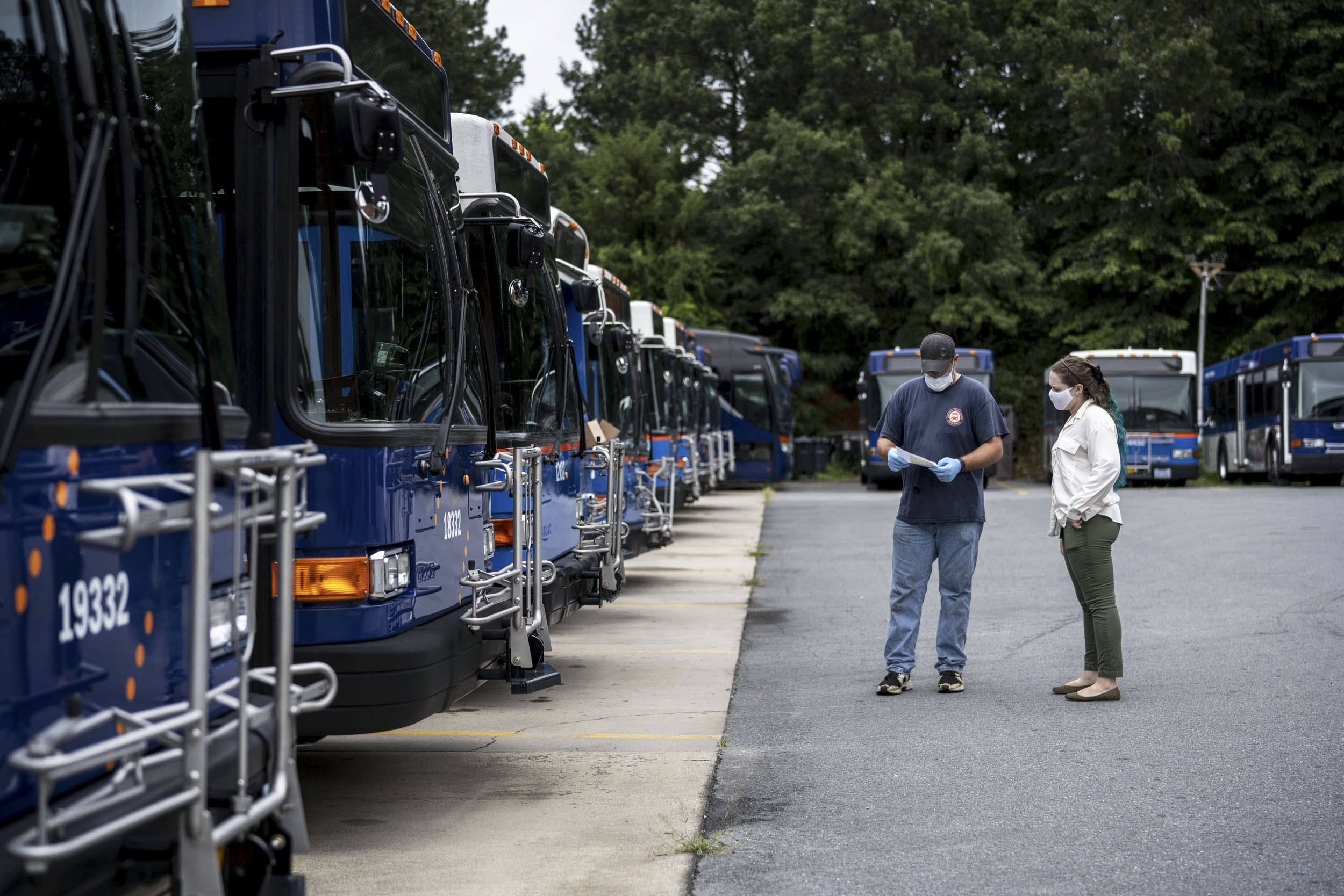Scott Anderson, left, talking to Allison Day, right in front of UVA transportation buses