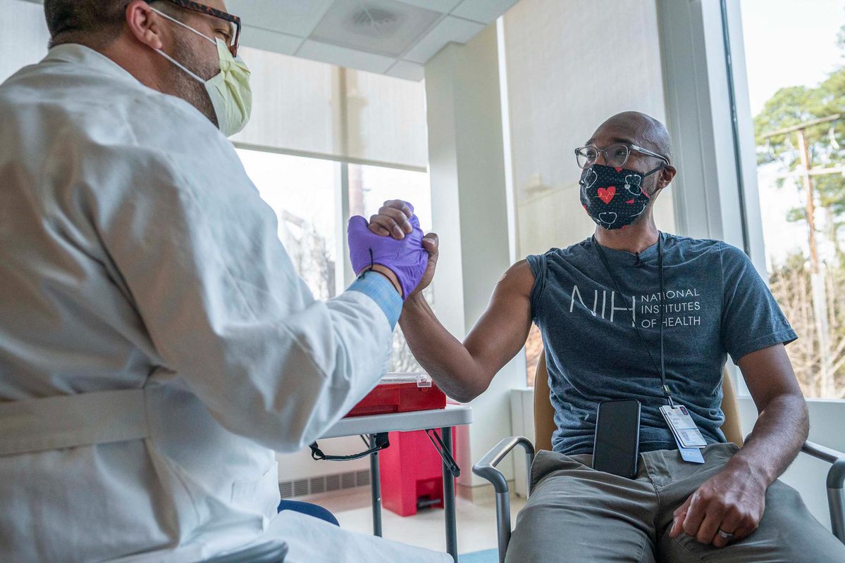 Dr. Taison Bell giving a high five to the person who vaccinated him