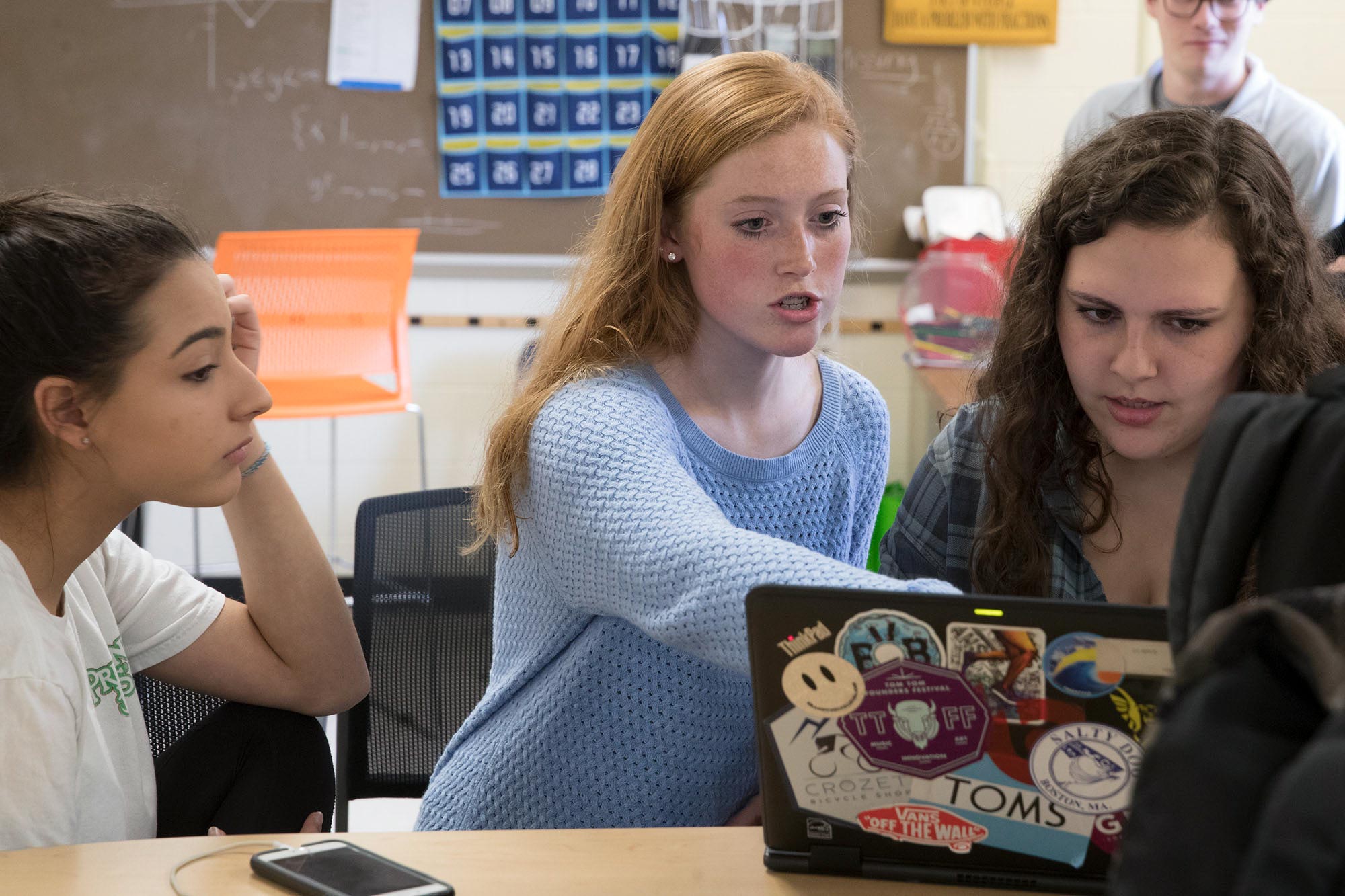 Students sit at a table together and work on a computer