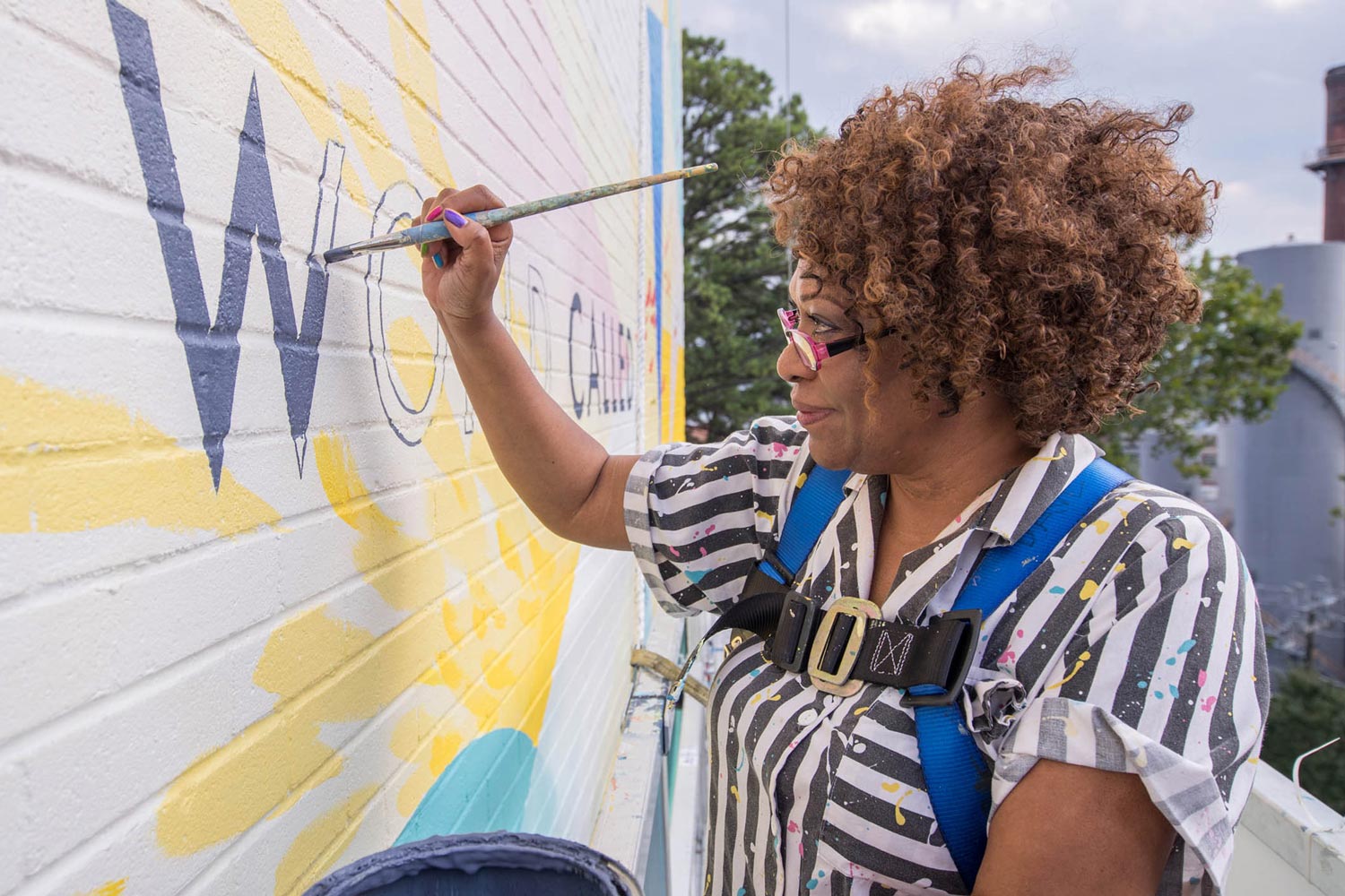 Rita Dove painting a wall on the outside of a building