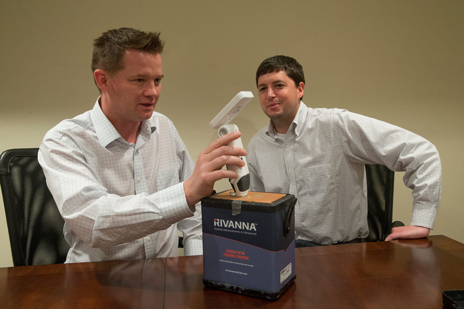 Kevin Owen (left) demonstrates the Accuro device’s spine-finding capabilities through layers of synthetic skin while his co-founder Will Mauldin looks on.