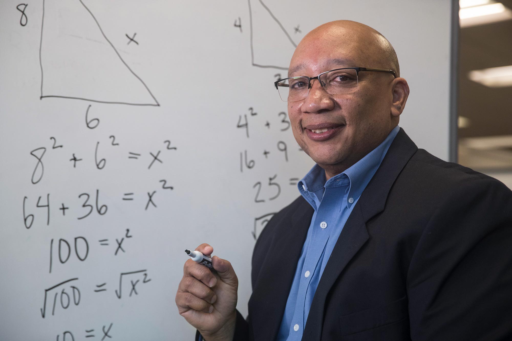 Robert Berry facing the camera with a dry erase marker in his hand next to math equations