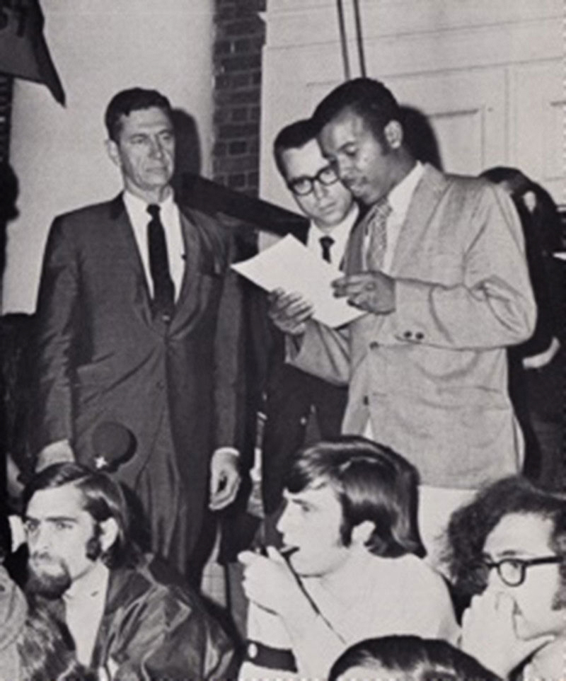Black and white image of James Roebuck, center, reads a list of student demands to University President Edgar Shannon, left, 