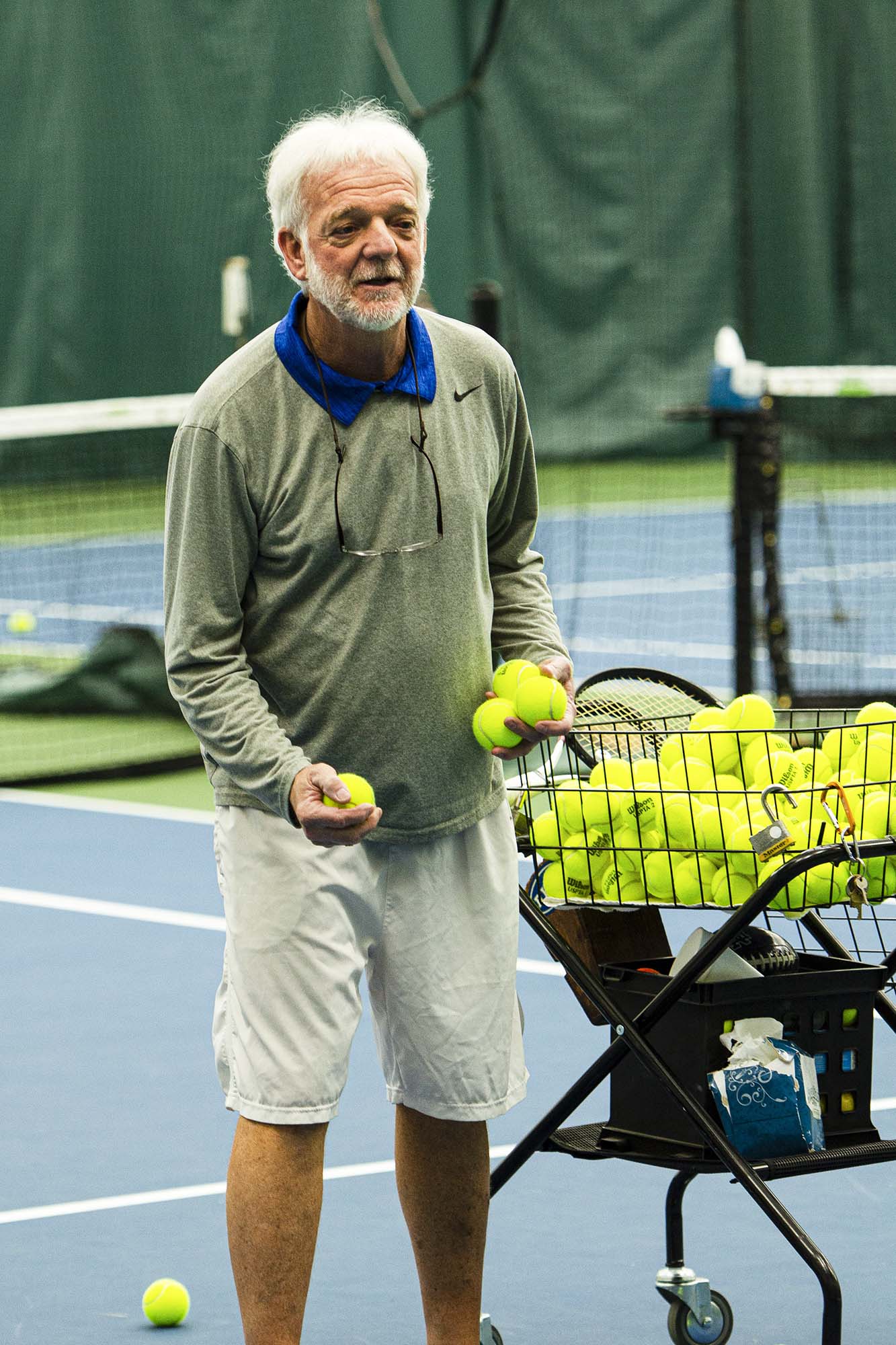 Manilla collecting tennis balls to place back in the tennis ball cart