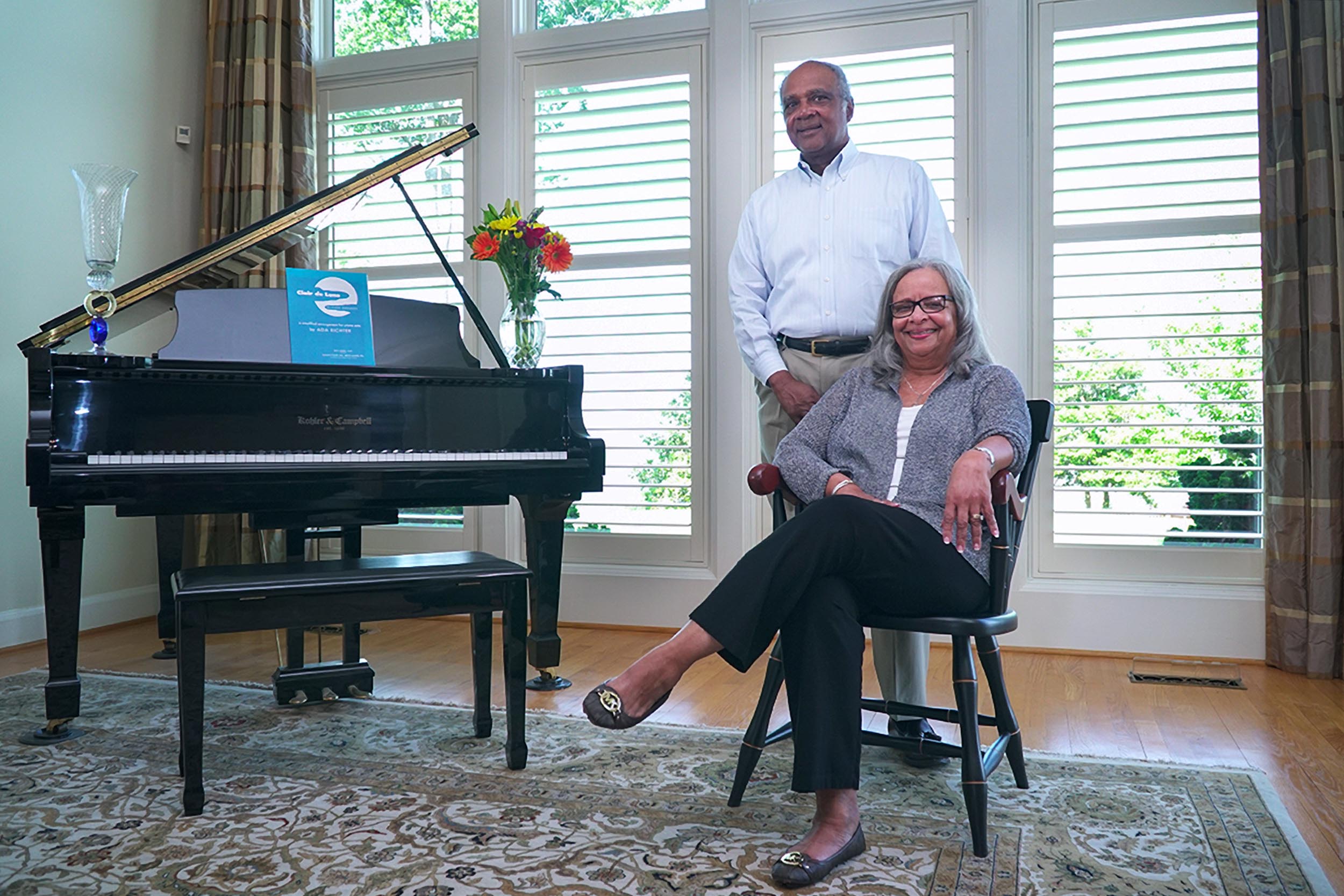 Sandra and Lemuel Lewis, pose next to a piano together