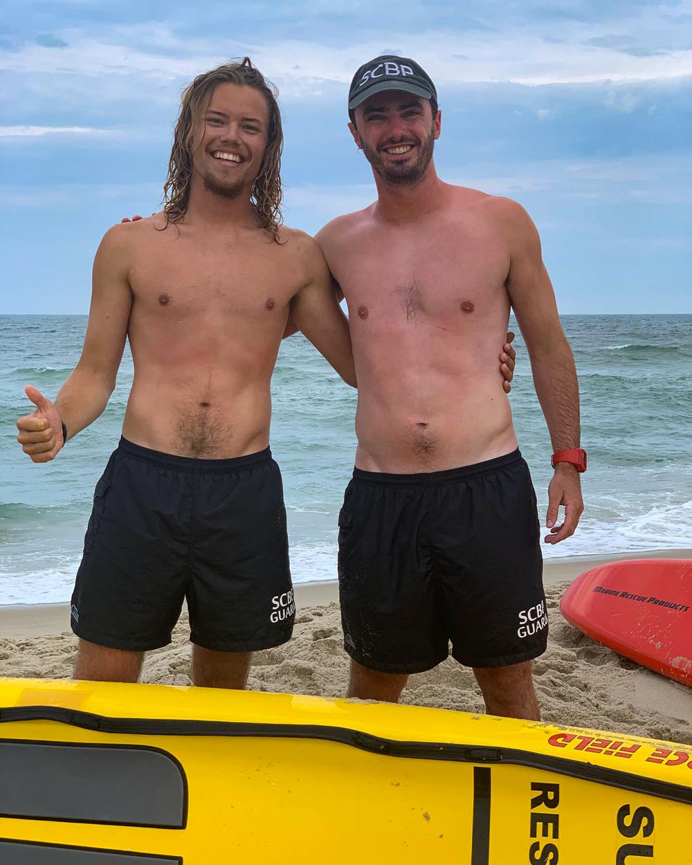 Osborne, right, and fellow lifeguard Scott Meggitt, left stand together on the beach pose for a picture