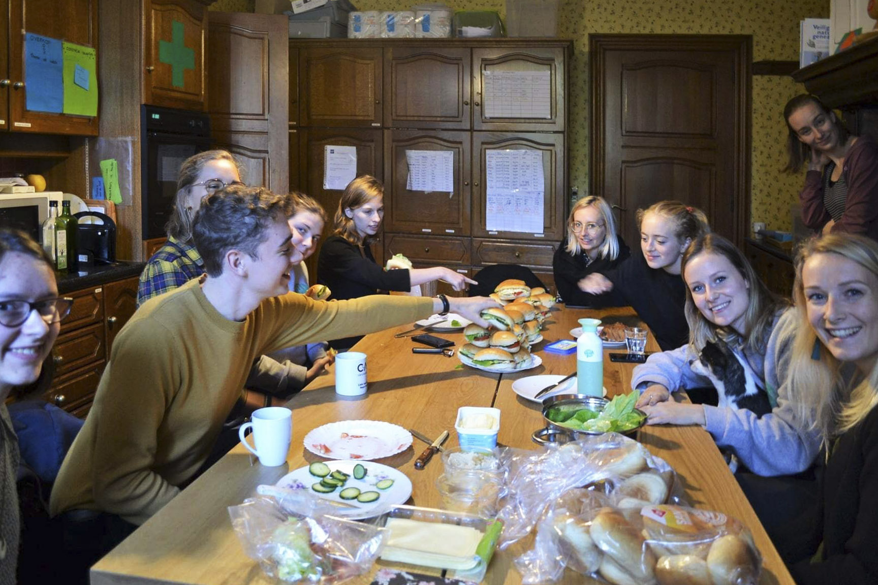 Group of friends gather around a table to make and eat sandwiches together