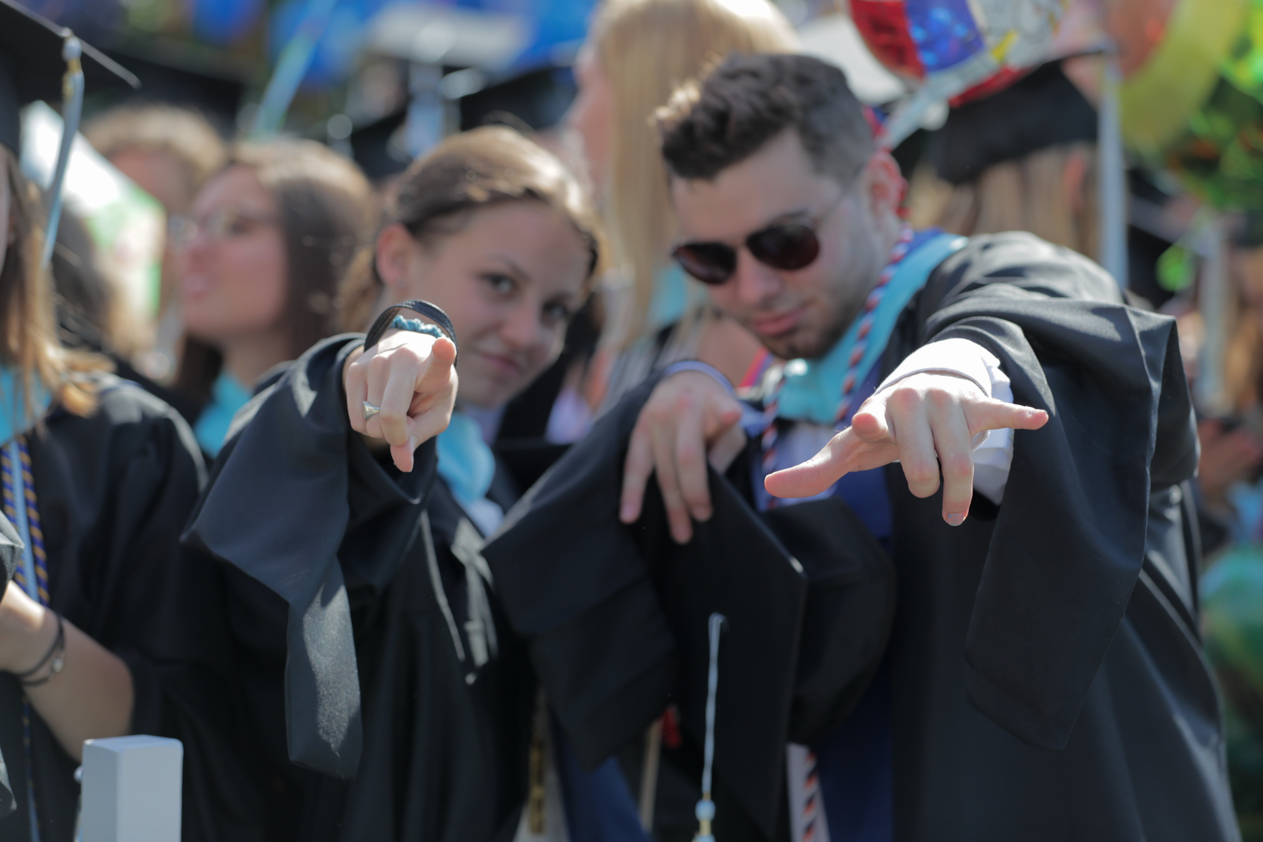 Graduates pointing at the camera