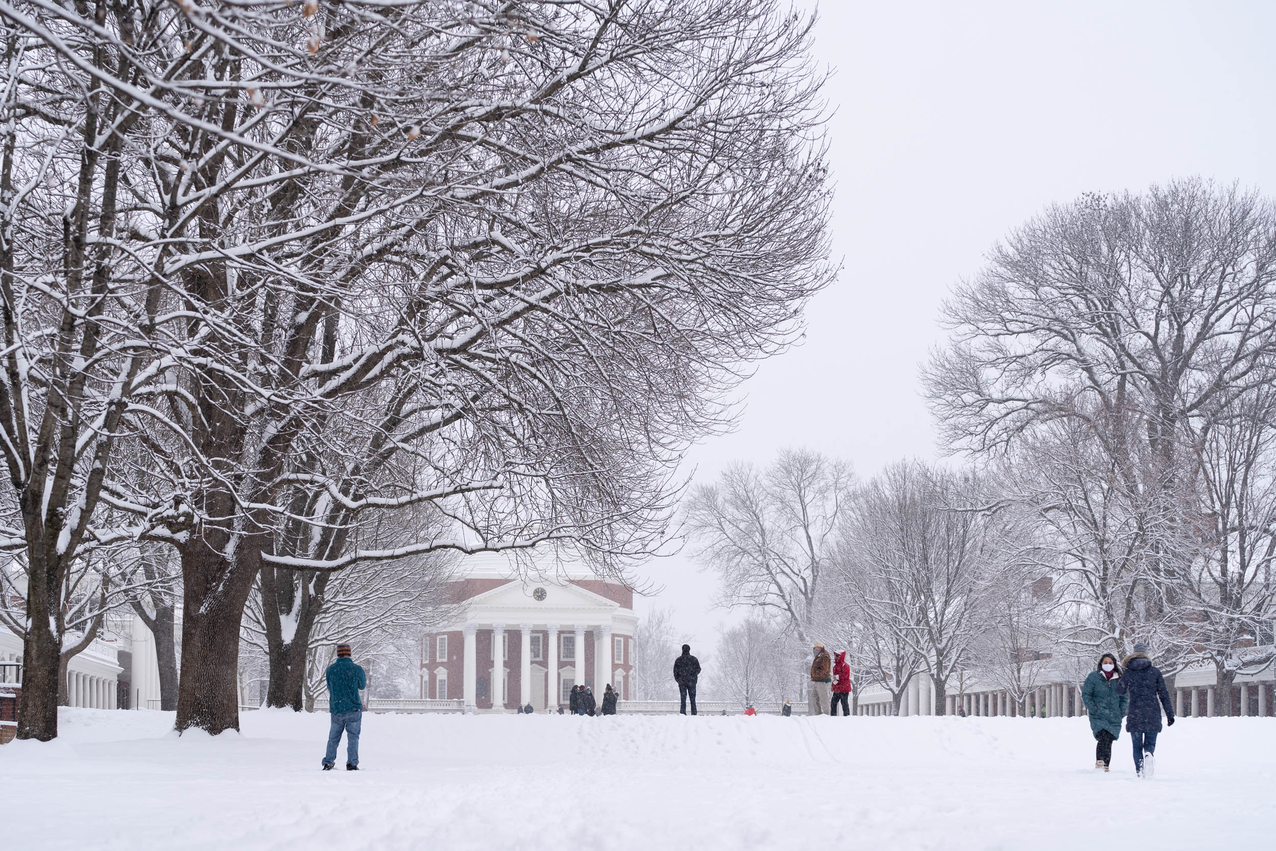 Students walking on a snow covered Lawn