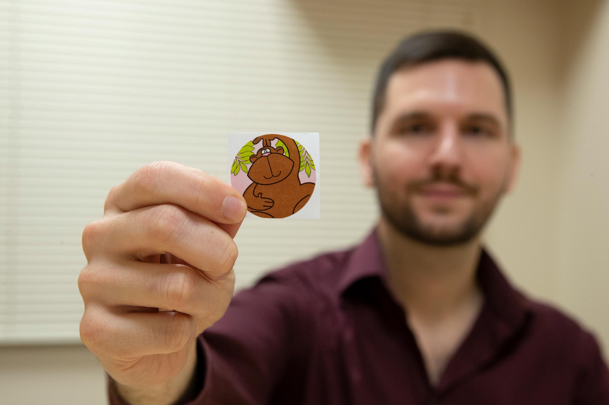 Beeler-Duden, out of focus, holding a sticker of monkey, in focus,