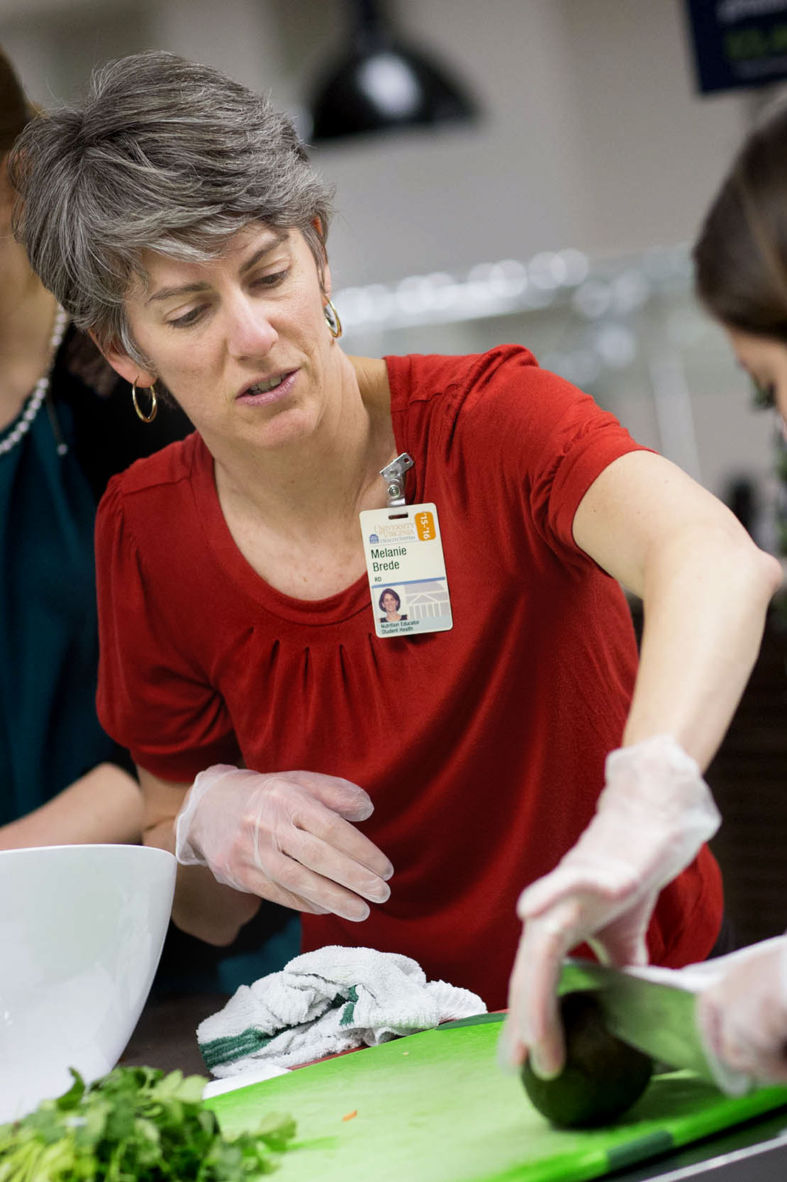 Melanie Brede helping a student cut a vegetable 