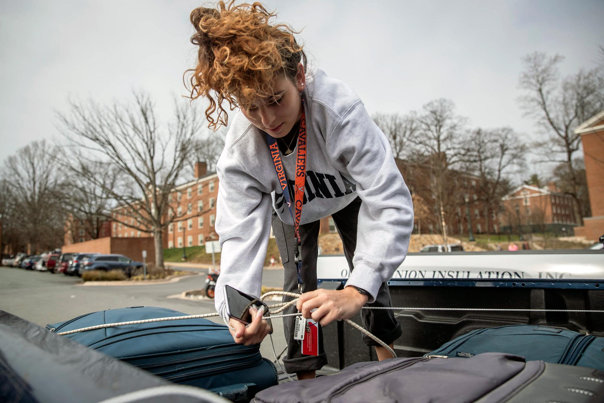 Taina Santana tying a rope over her luggage that is in the back of a pickup truck