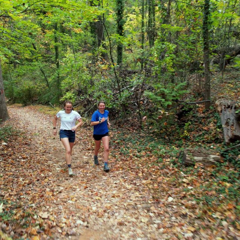 Emily Carder and Sophia Gibby running together on a wooded trail
