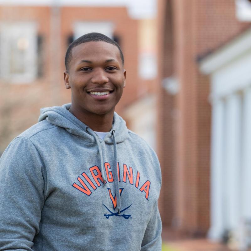 Antonio Brodie Jr. wears a gray sweatshirt with the Virginia Cavaliers logo and smiles at the camera