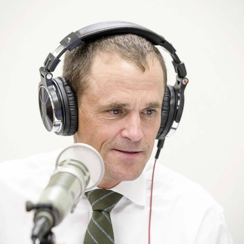 Jim Ryan wears headphones and speaks into a microphone