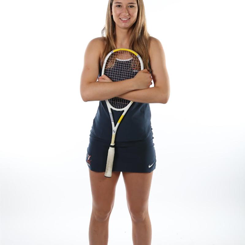Sarah Doss stands and clinches her squash racquet with both hands tight against her chest