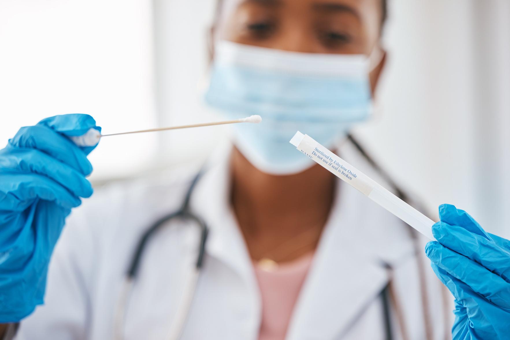 A doctor putting a qtip sample into a test tube