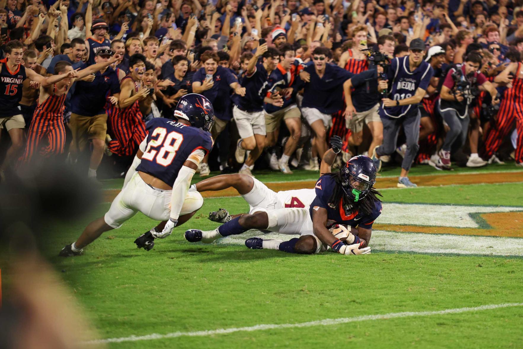 Candid portrait of UVA defensive back Ja’son Prevard secures the game-sealing interception as fans prepare to storm the field to stamp the Cavaliers’ win over Florida State.