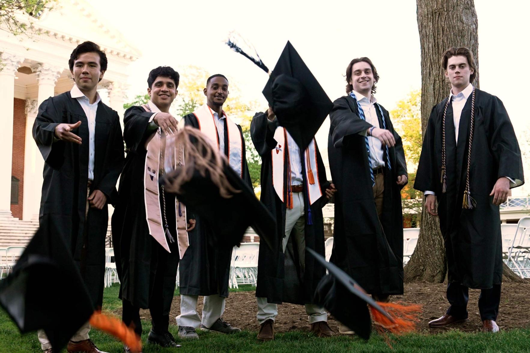A group of grads on the Lawn throwing their caps at the camera