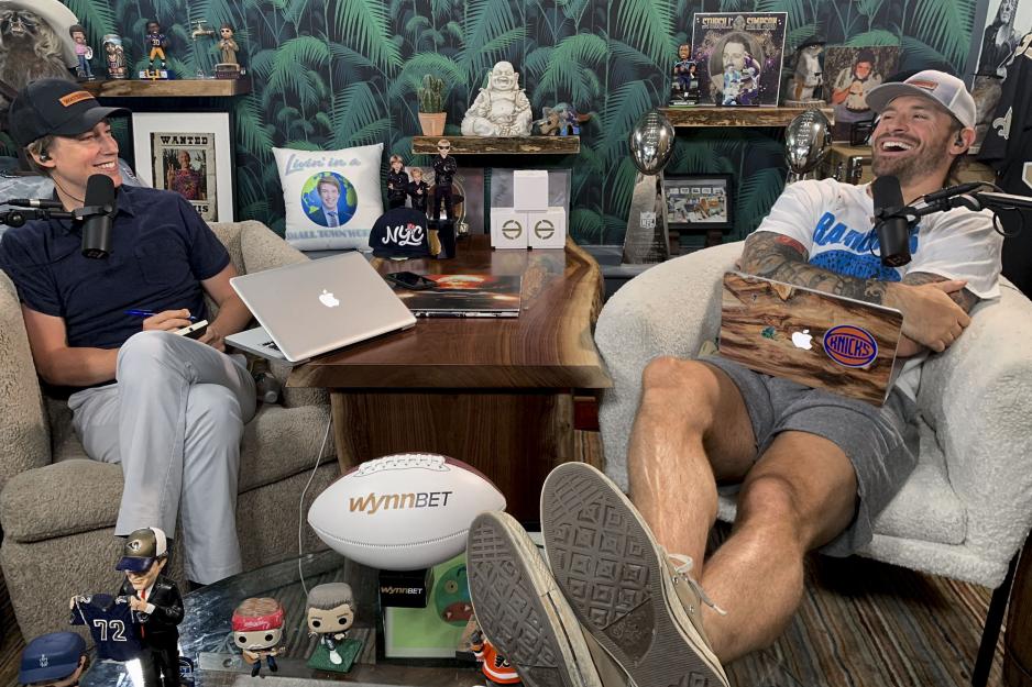 Alumnus Macon Gunter co-hosts,left, and Chris long, right, recording a podcast sitting in chairs with their laptops and microphones