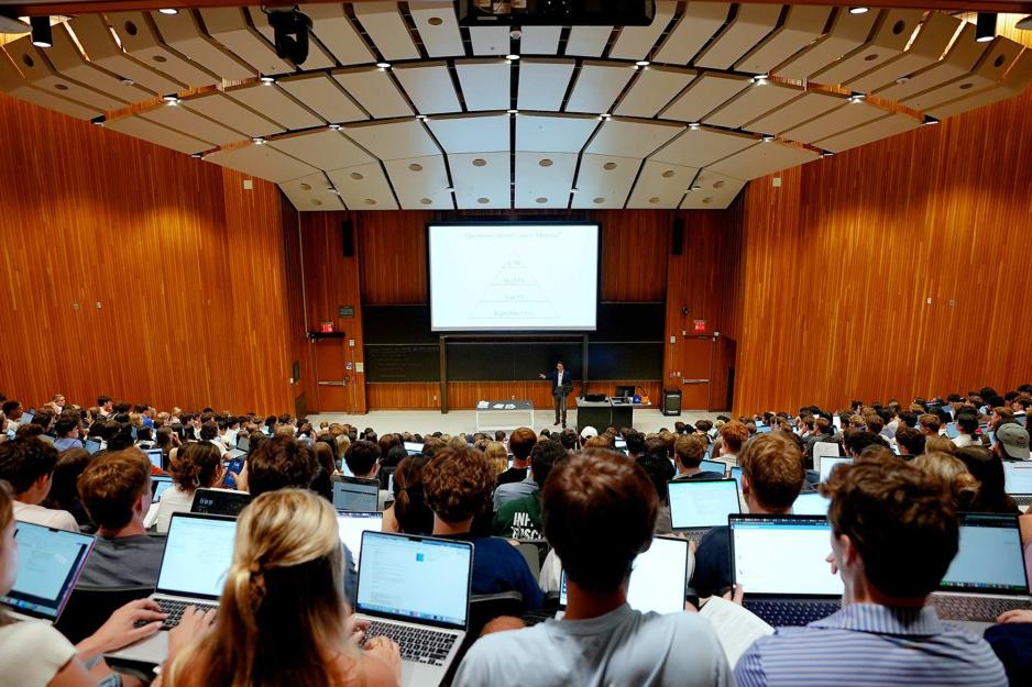a lecture hall full of students taking notes on laptops