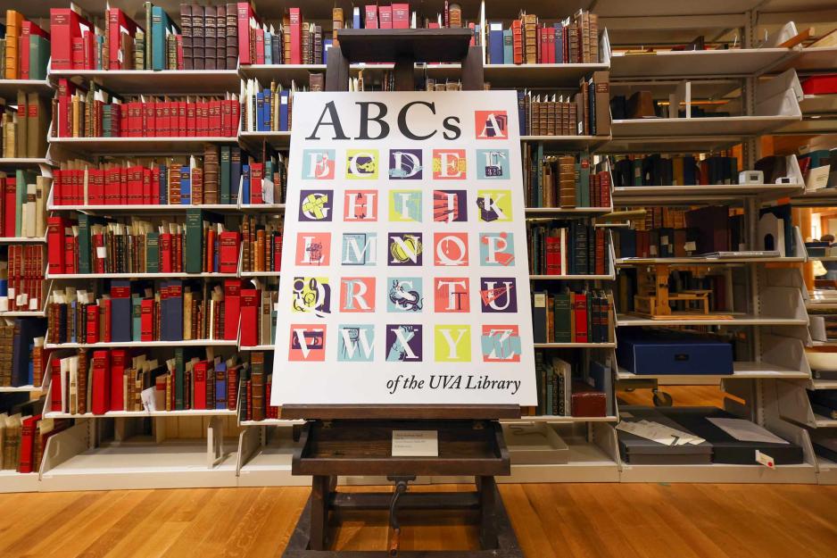 a poster with a stylized illustration of the English alphabet sitting on an easel in a library.