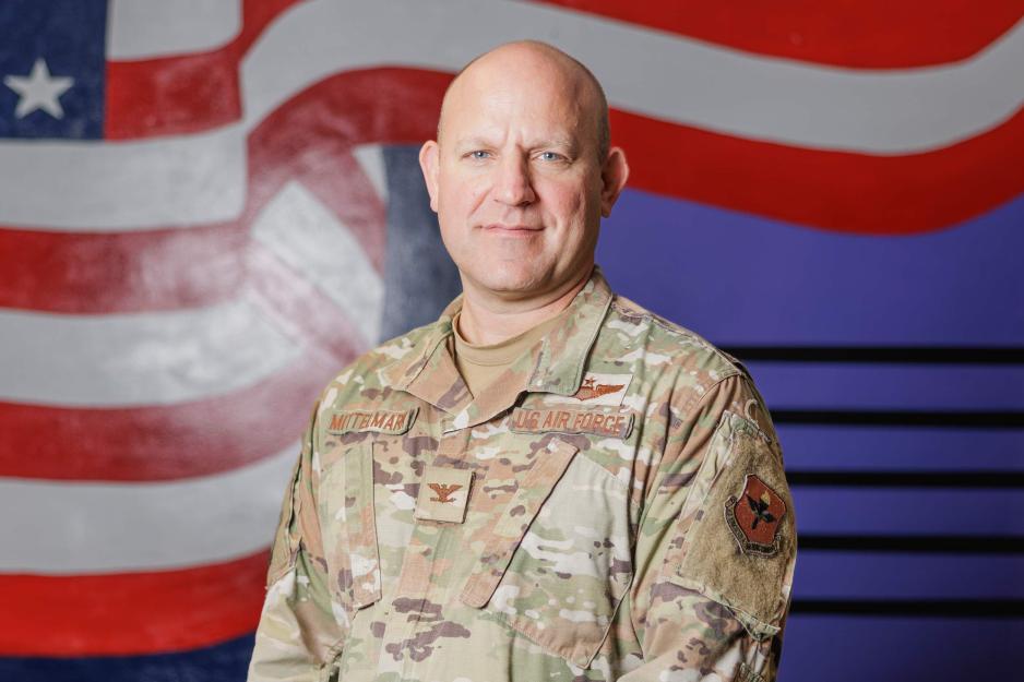 U.S Air Force Col. Cary Mittelmark stands in front of a mural of the U.S. Flag