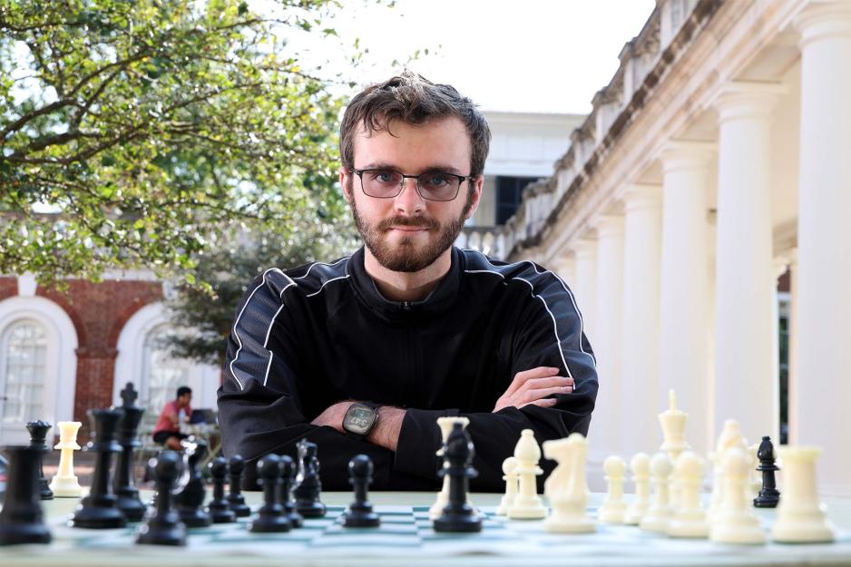 Fourth-year student Jason Morefield poses behind his chess pieces 