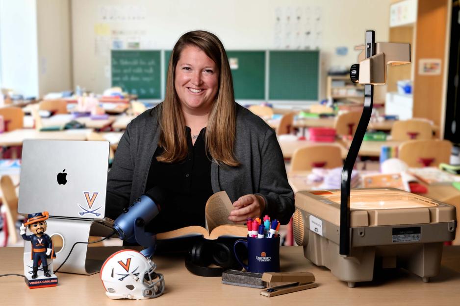 Anne Jewett sitting at her desk with a virtual classroom background