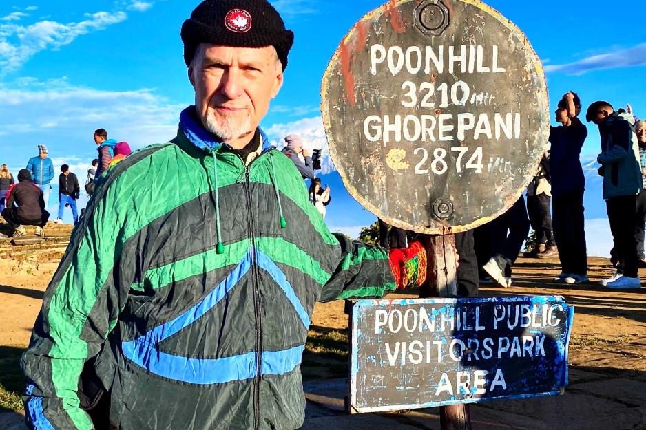 James Arnold stands by a mile marker on Poon Hill opposite Mount Annapurna in Nepal 