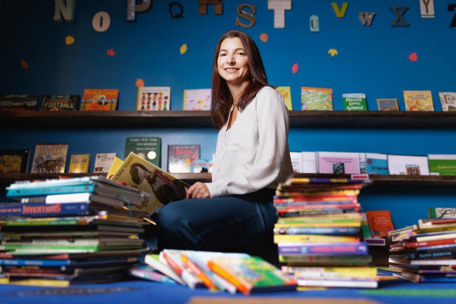 Associate Professor Jamie Jirout sitting on the floor, surrounded by children's books