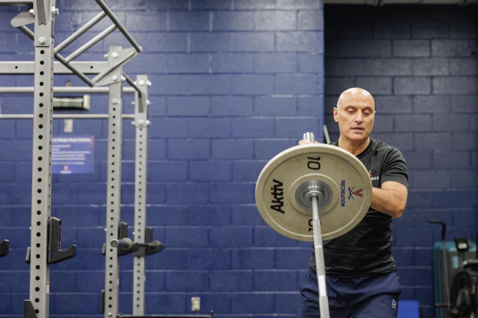 Hamid “Jim” Karimi putting a large weight on a bar at the North Grounds Recreation Center